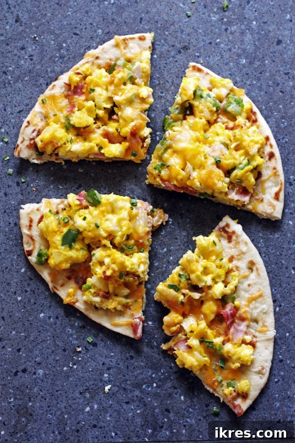 Quick Tortilla Breakfast Pizza 7 Sliced breakfast pizza revealing the layers of fluffy egg, ham, peppers, and melted cheese on a crispy tortilla.