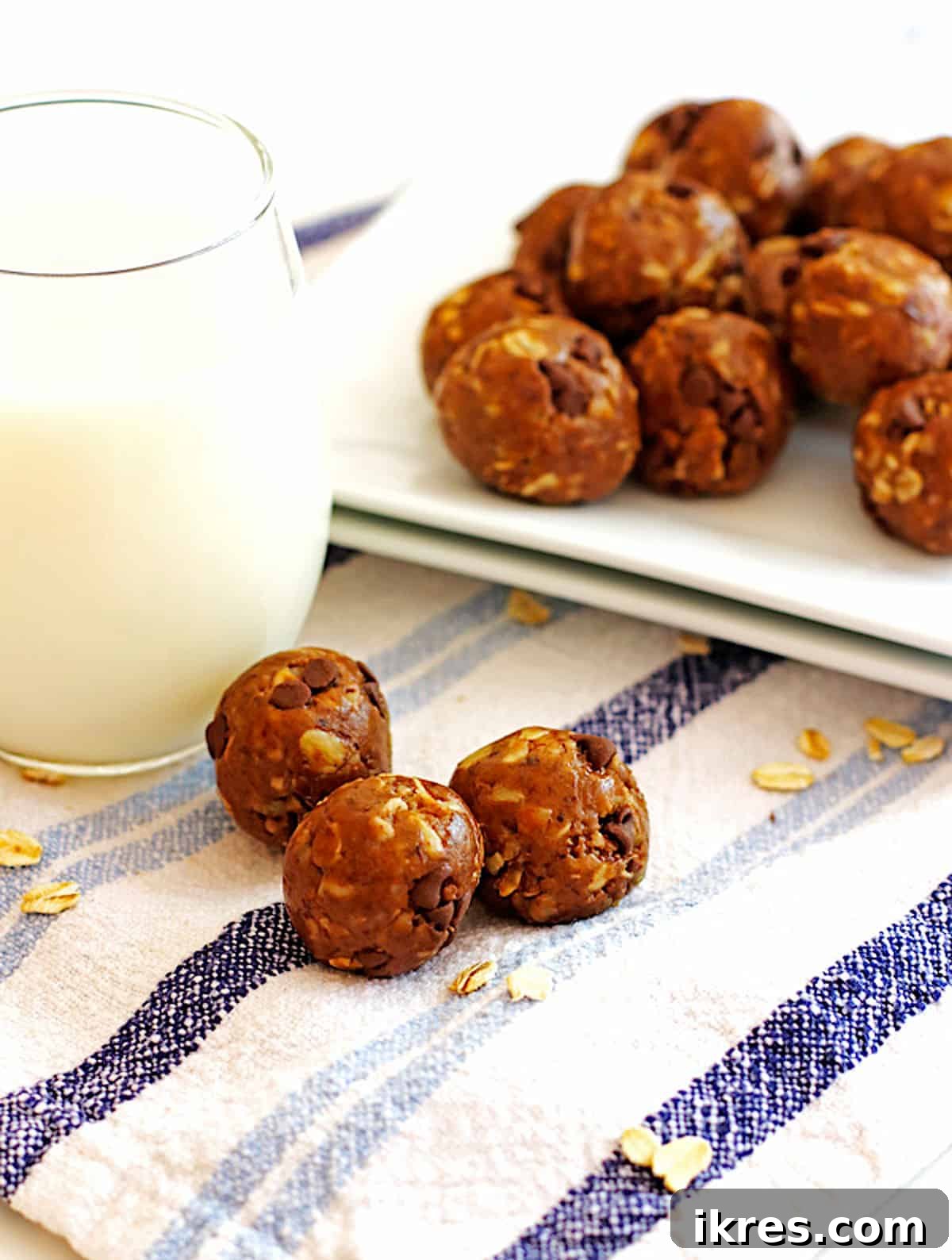 Peanut Butter Power Bites 2 A plate of golden peanut butter energy bites, with a hand reaching for one, a glass of milk, and three more bites in the foreground, ready to be enjoyed.