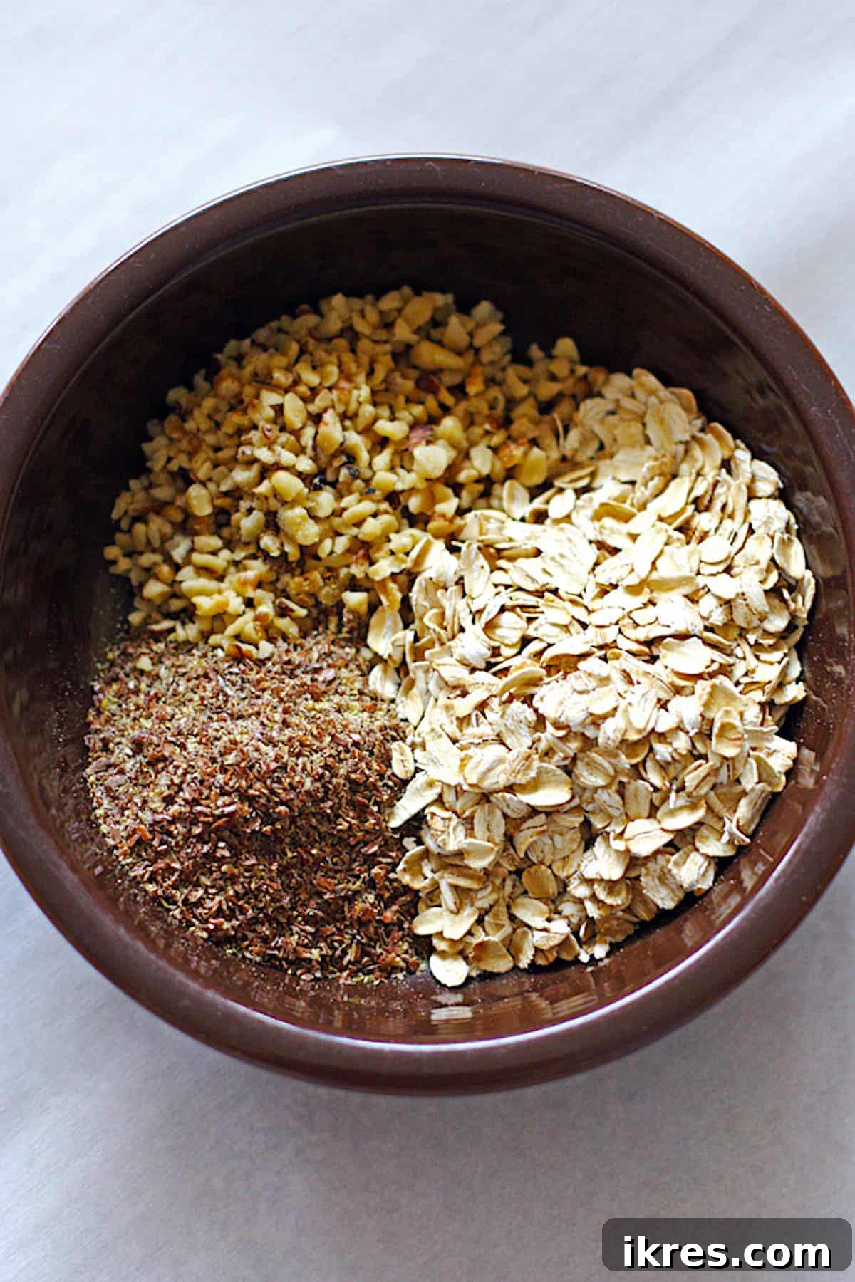 Peanut Butter Power Bites 3 A brown bowl containing the dry ingredients for peanut butter energy balls: ground flax seeds, oats, and walnuts, perfectly mixed.
