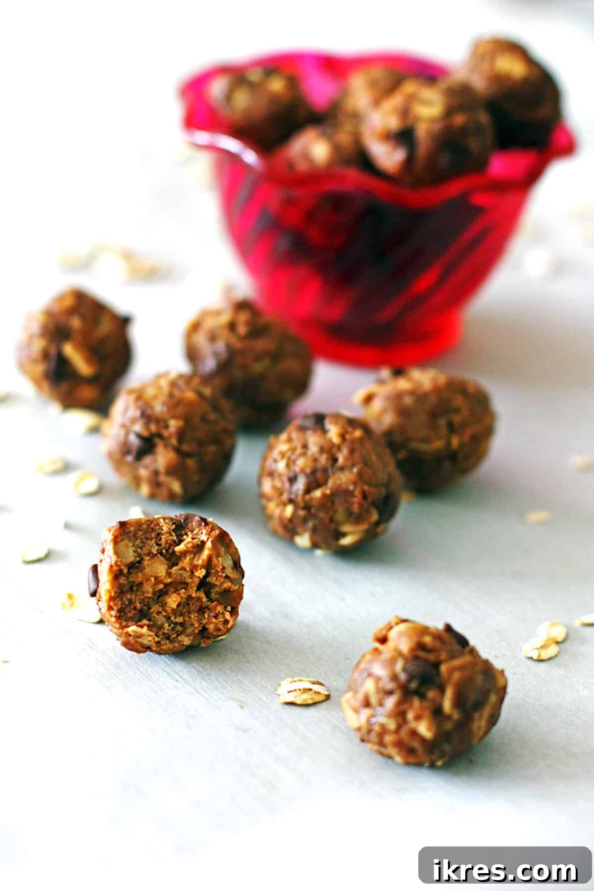 Peanut Butter Power Bites 4 Peanut butter energy balls arranged invitingly in front of a vibrant red bowl, with one bite taken out of a ball to reveal its delicious interior.