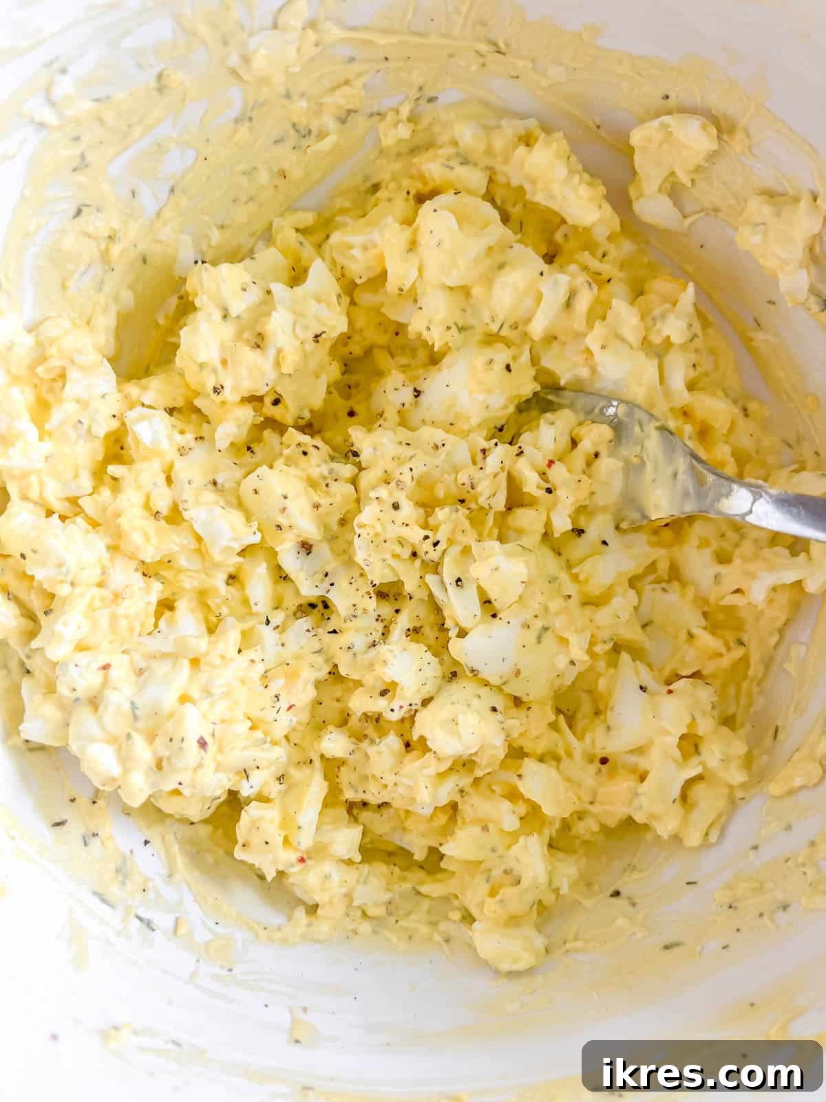 Creamy egg salad in a bowl after mixing all ingredients.