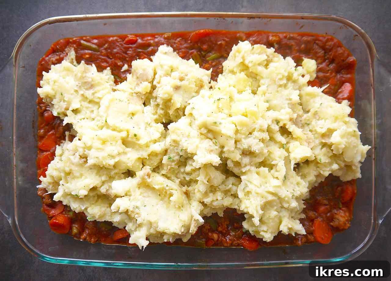 Rustic Paleo Ground Lamb Shepherd's Bake 6 Creamy potato and cauliflower mash being carefully spread over the lamb gravy in a baking dish.