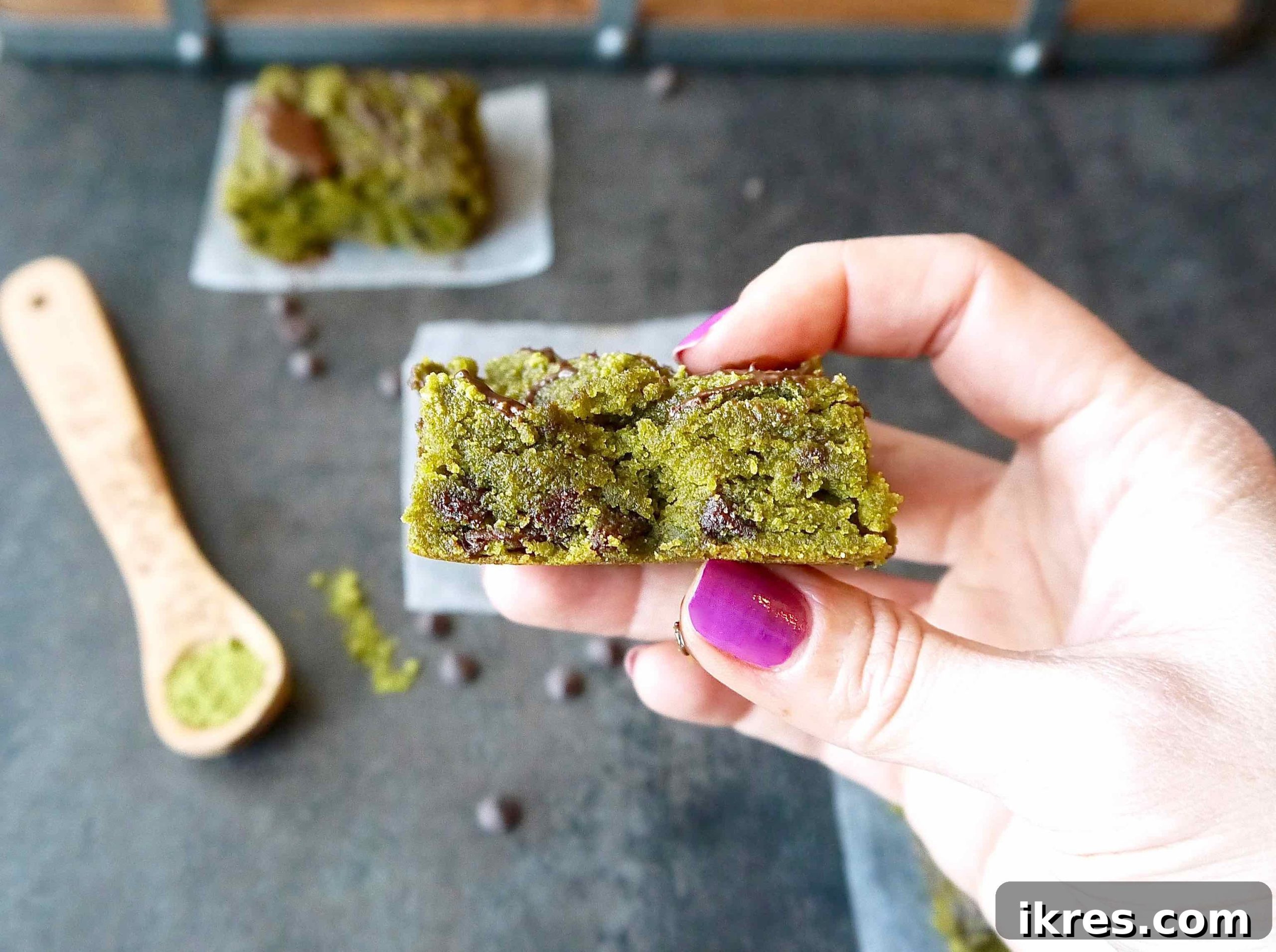 Almond Flour Matcha Brownies: A Paleo, Gluten-Free & Dairy-Free Delight 3 A big bite taken out of a vibrant green matcha blondie, showing its chewy texture and chocolate chips.