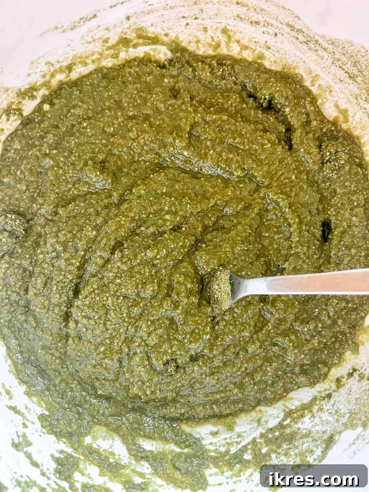 Almond Flour Matcha Brownies: A Paleo, Gluten-Free & Dairy-Free Delight 7 Wet and dry ingredients for matcha brownies being mixed together in a bowl, forming a thick green batter.