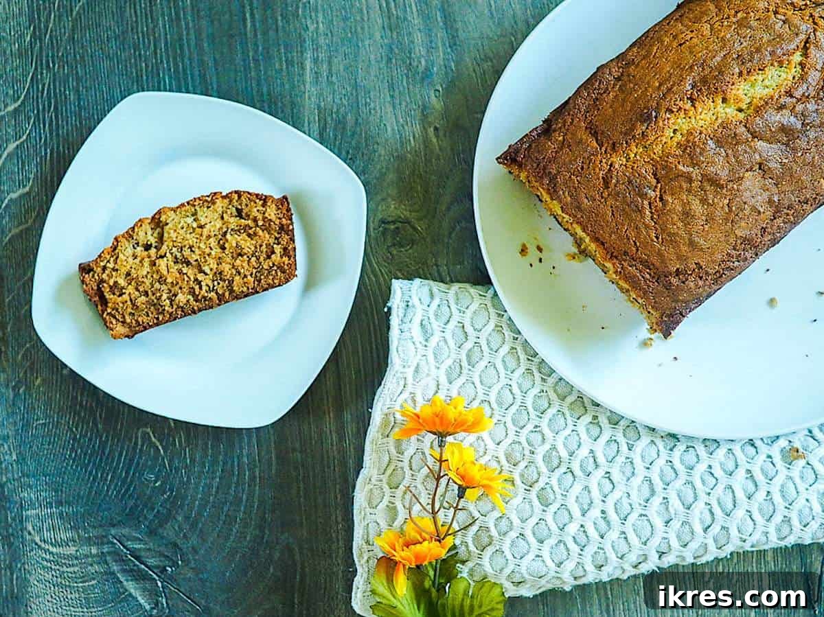 Perfectly Easy Bread Maker Banana Bread 2 A freshly baked loaf of moist bread machine banana bread on a white plate, with a perfectly sliced piece next to it, ready to be enjoyed.