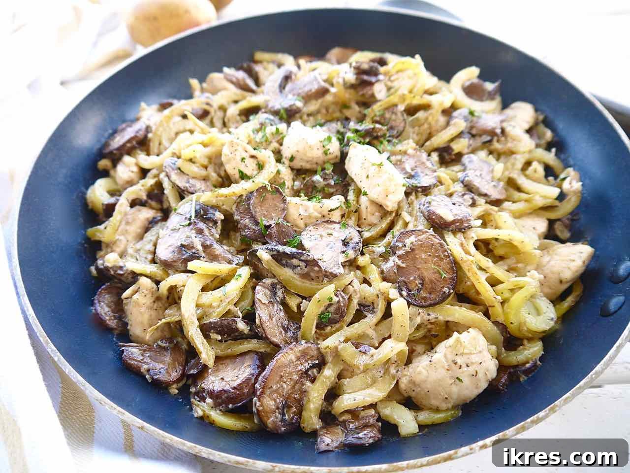 Chicken, mushroom, and spiralized potato casserole baking in a skillet, showing off the golden-brown crust.