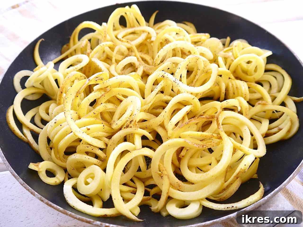 Spiralized potatoes arranged in a frying pan, ready for baking.