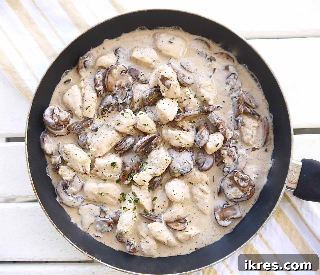 Cooked chicken, mushrooms, and coconut cream combined in a frying pan to create the casserole sauce.