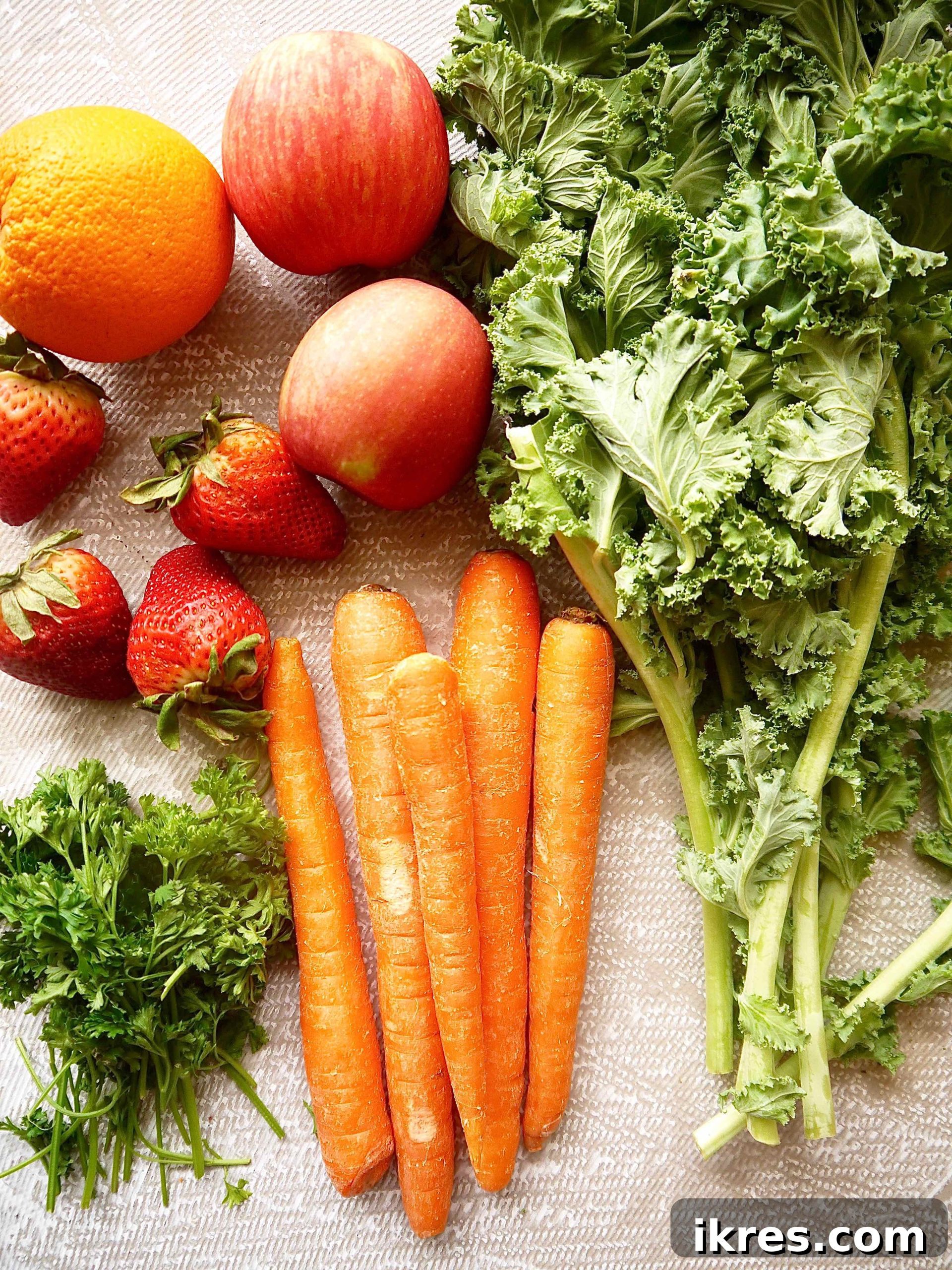 Green Garden Glow 3 A vibrant selection of fresh, organic ingredients including bright carrots, leafy kale, crisp apples, fresh parsley, juicy oranges, and ripe strawberries, neatly arranged and ready for juicing.