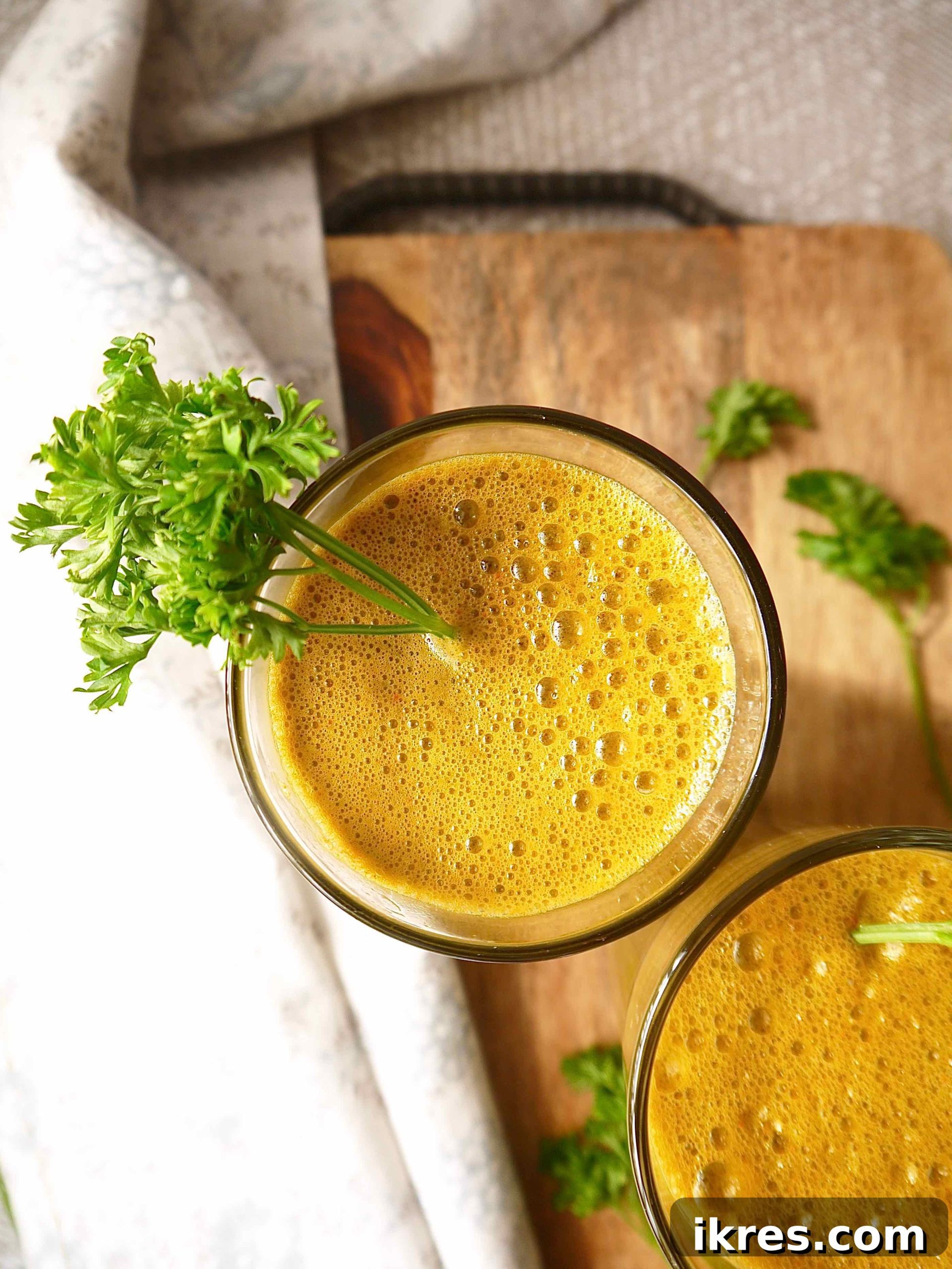 Green Garden Glow 4 A glass of freshly made Kale Carrot Juice with a delicate sprig of parsley hanging gracefully over the rim, perfectly ready to be enjoyed.