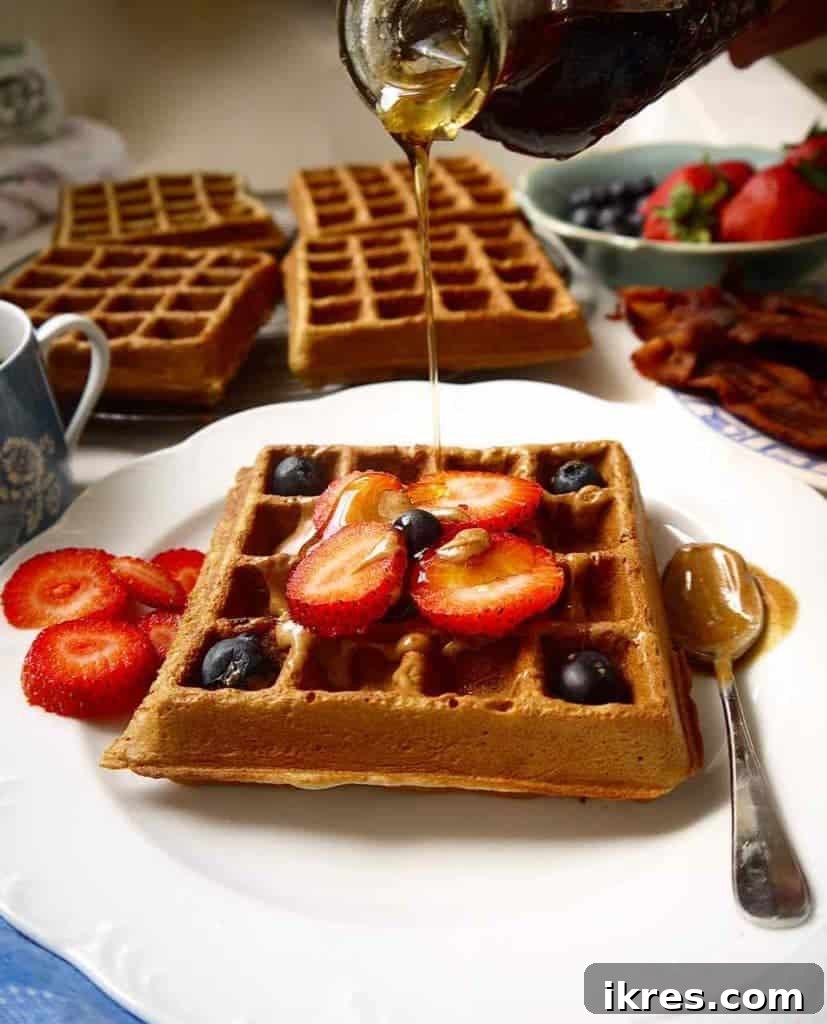 Irresistibly Crispy Paleo Berry Waffles 2 Golden brown crispy Paleo Berry Waffles stacked on a white plate with fresh berries