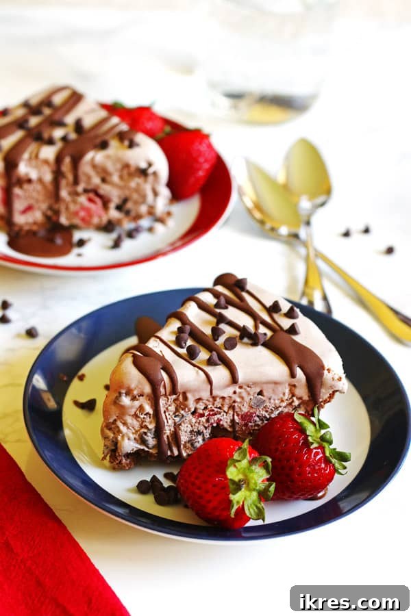 Two slices of ice cream pie. Each slice is on a plate and garnished with strawberries and chocolate chips
