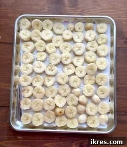 Freeze Bananas the Right Way for Smoothies 13 Sliced bananas laid out in a single layer on a parchment lined baking sheet.