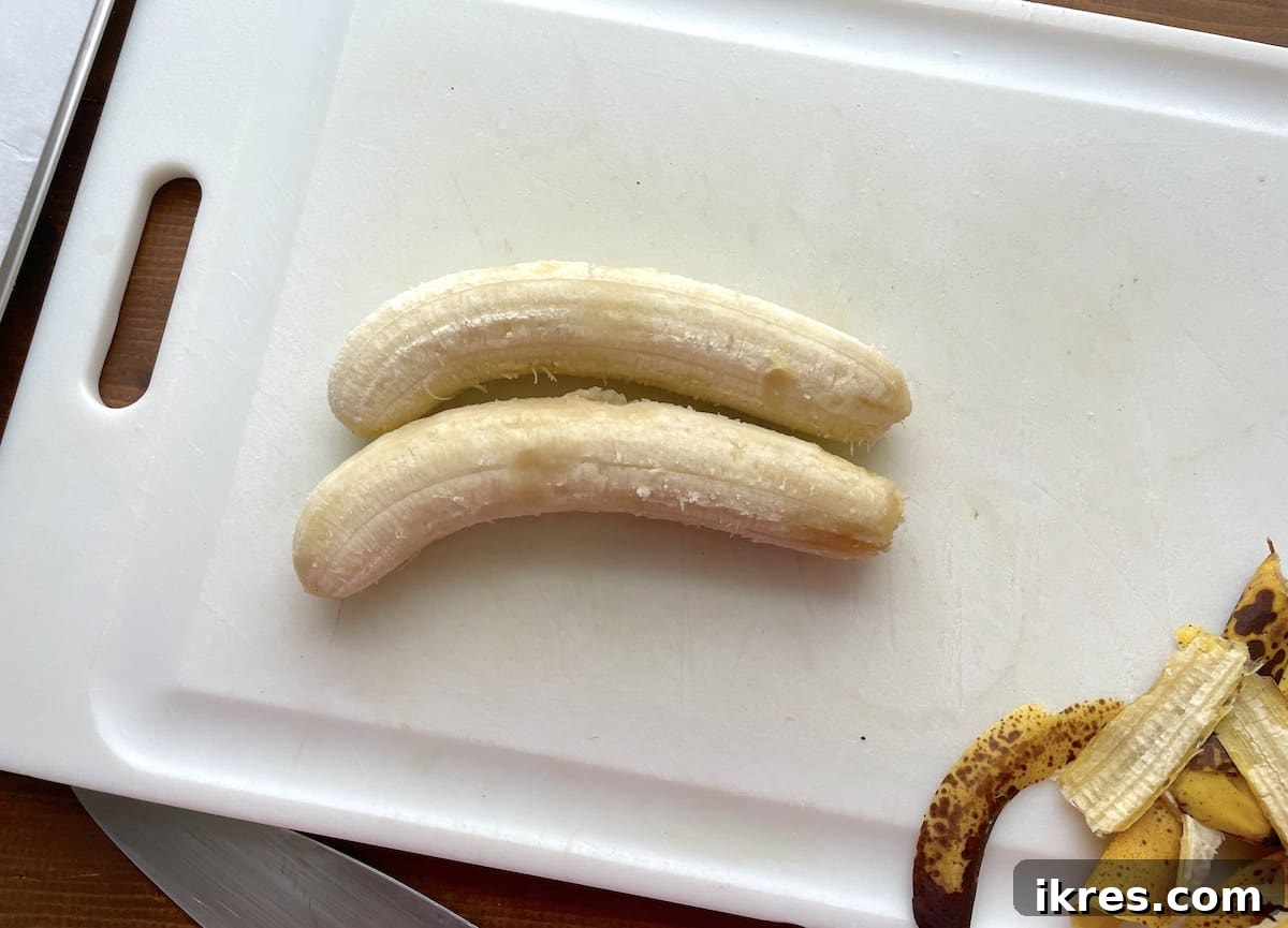 Freeze Bananas the Right Way for Smoothies 4 Two ripe bananas on a white cutting board ready to be sliced.