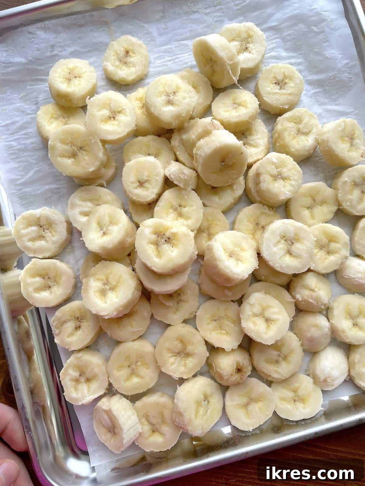 Freeze Bananas the Right Way for Smoothies 7 Frozen banana slices on a parchment lined baking sheet.