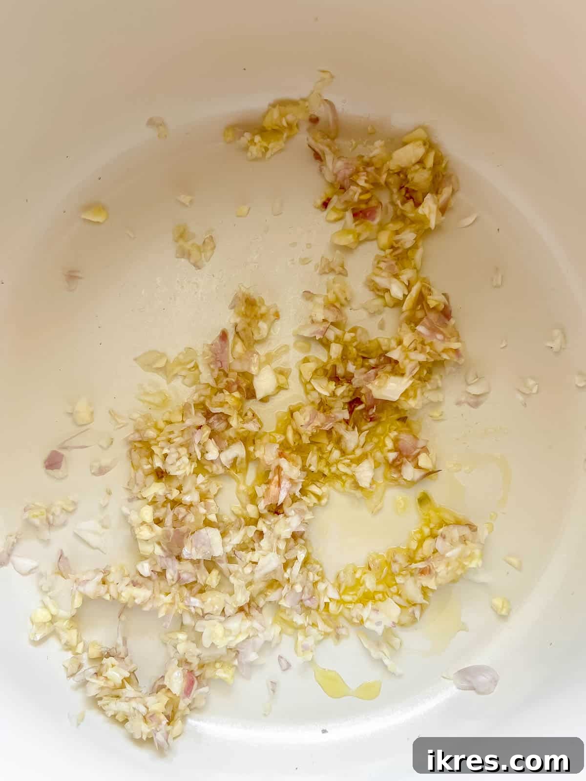 Minced onion and garlic sautéing in a pan with olive oil.