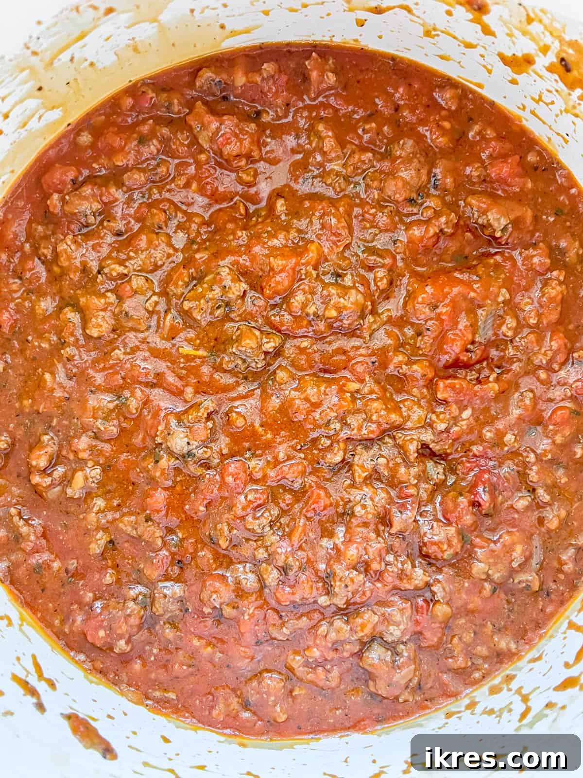 Marinara sauce added to the ground beef and tomato paste mixture, simmering gently.