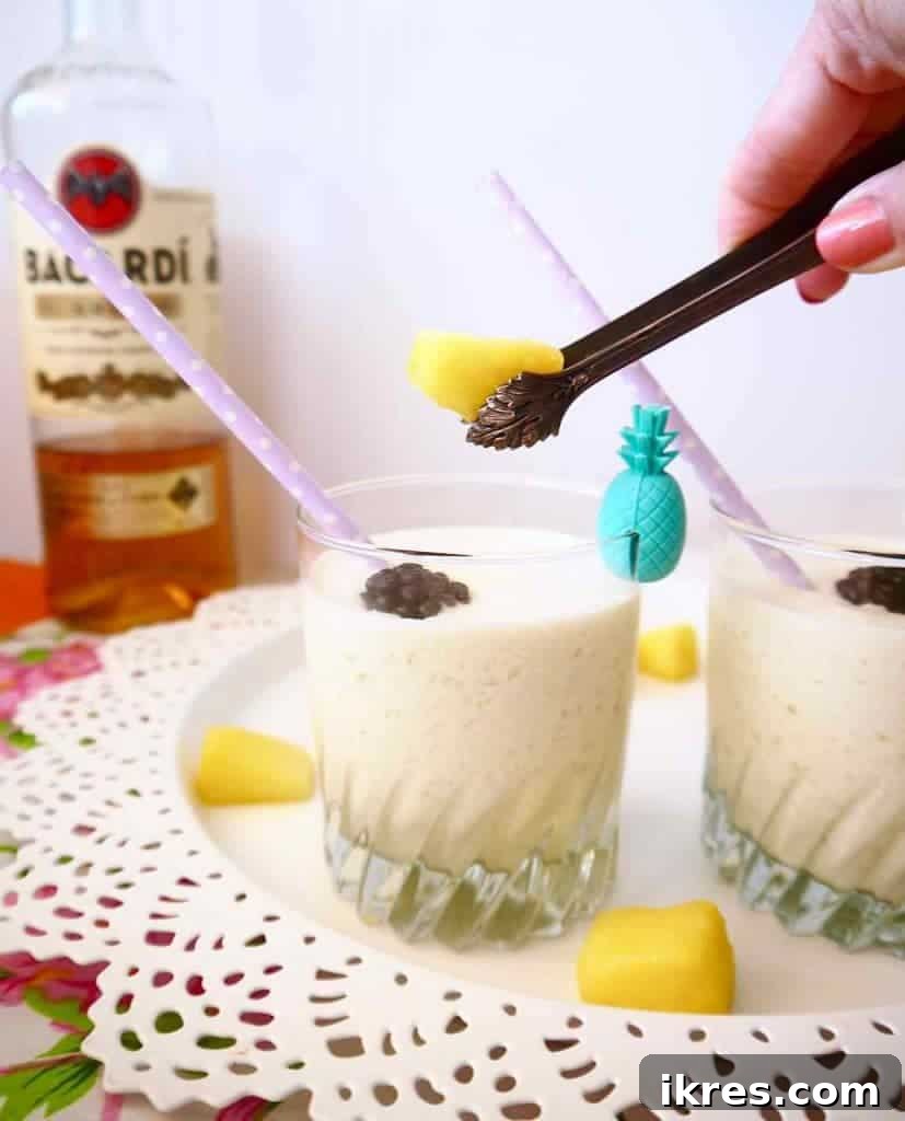Ingredients for a Piña Colada laid out: pineapple chunks, coconut cream, pineapple juice, rum, and maple syrup.