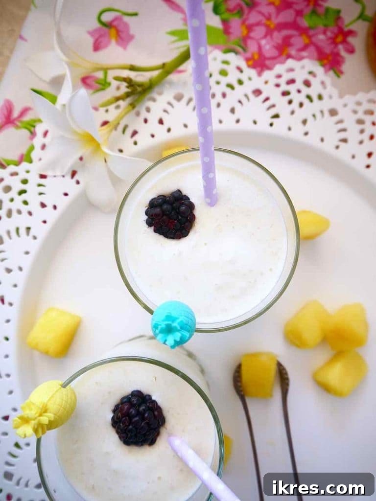 A hand holding a tall glass of all-natural Piña Colada, showcasing its thick and creamy texture.