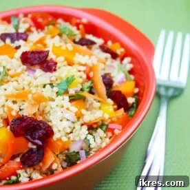 Vegetable quinoa salad with carrots and cranberries on a red plate.