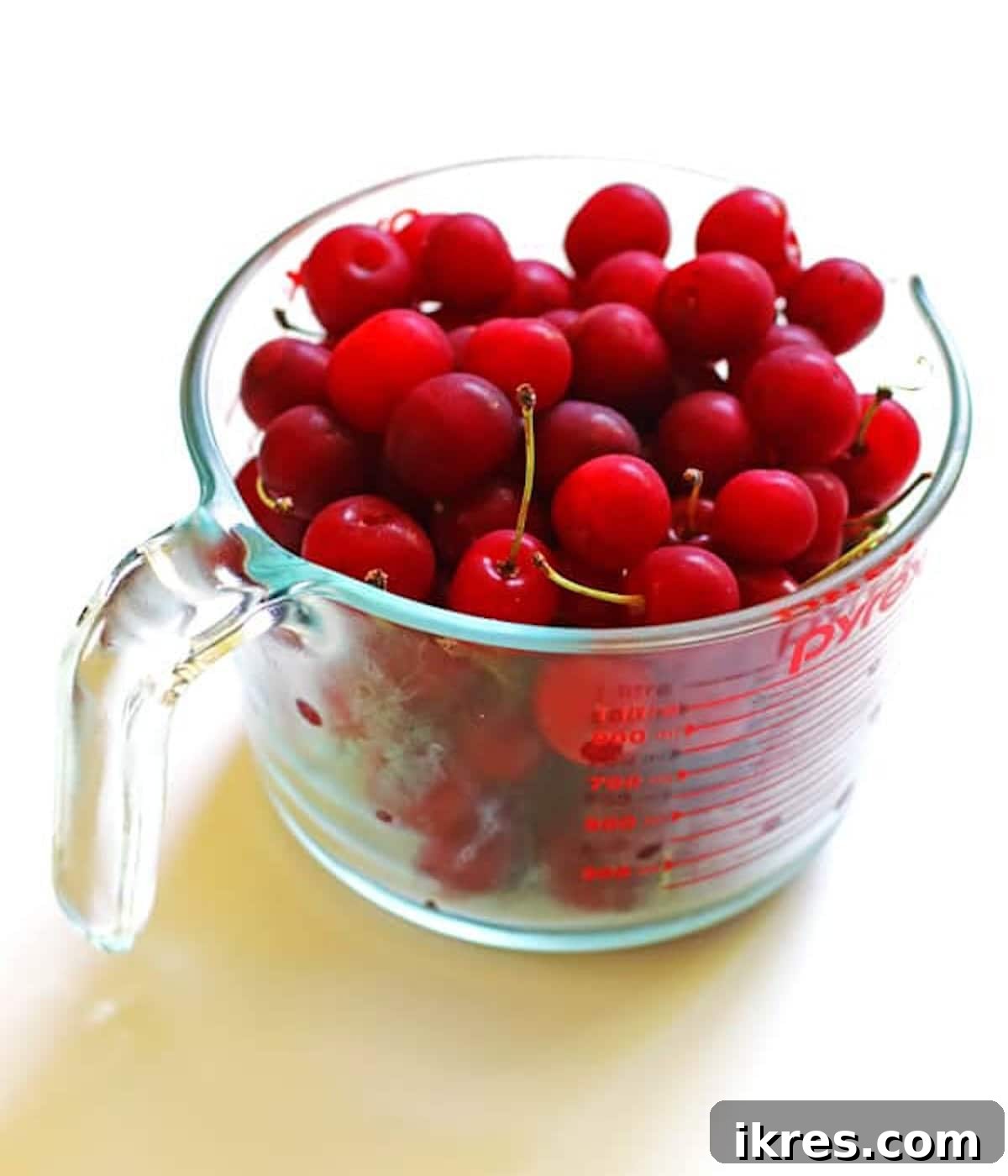 A pyrex cup of washed cherries.