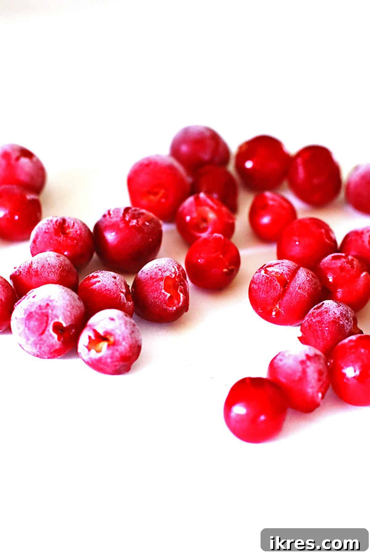 Frozen pitted cherries on a white board.