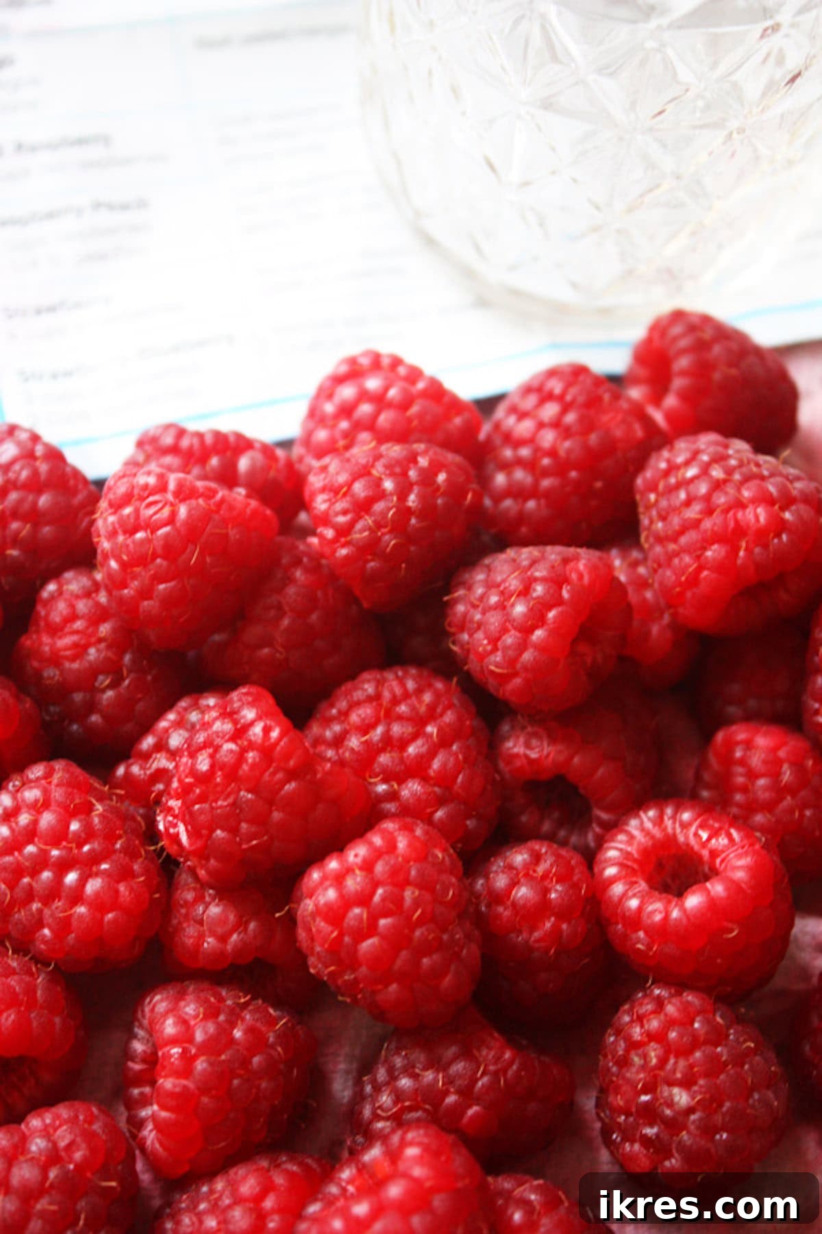 Ripe, fresh raspberries arranged on a baking sheet, ready for preparation.