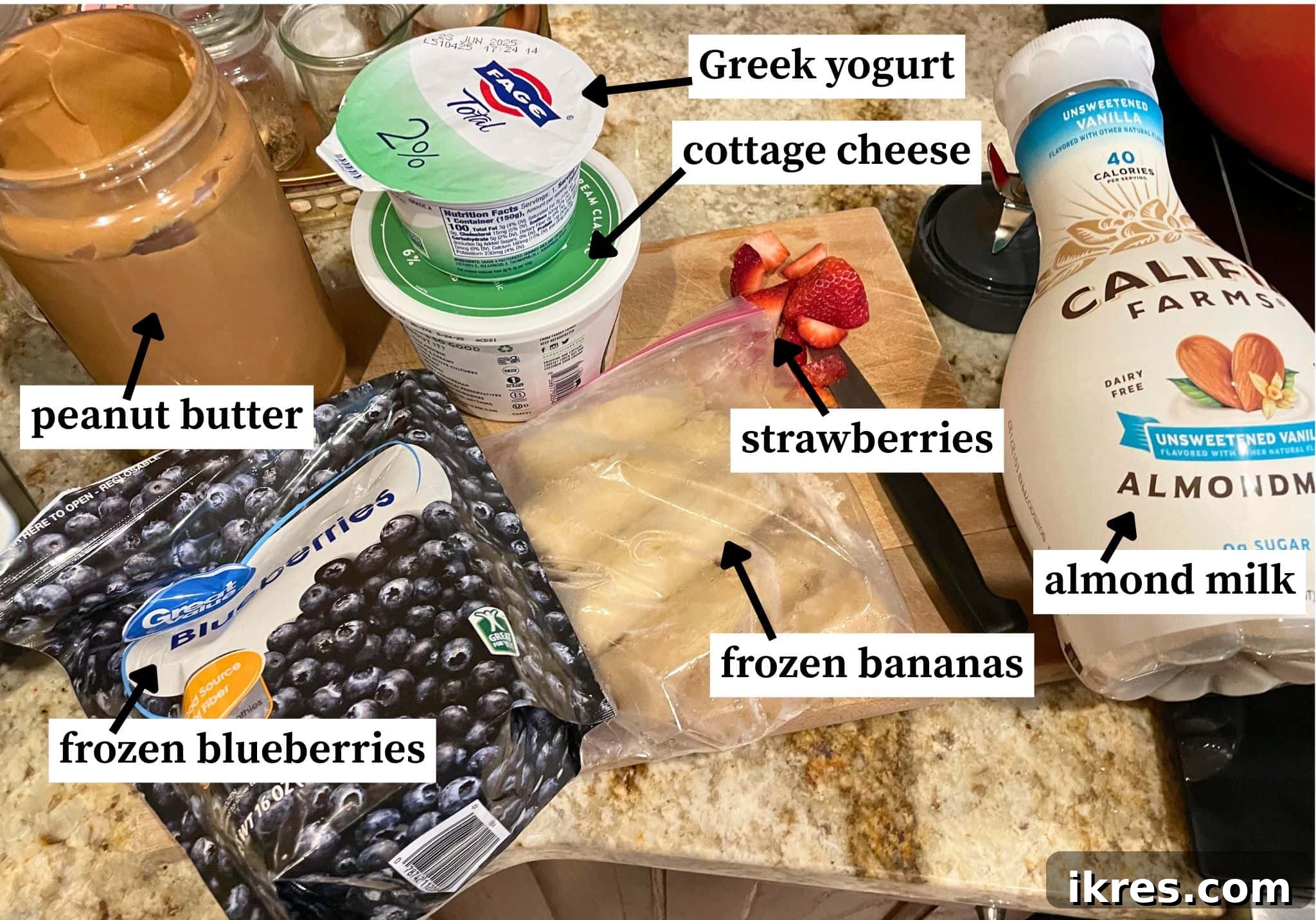 The ingredients needed to make a blueberry, banana, and peanut butter smoothie - laid out and labeled. Milk, yogurt, bananas, peanut butter, and frozen berries.