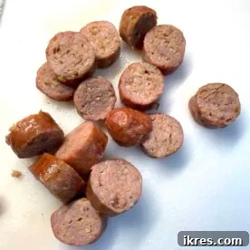 Oven-cooked, sliced Italian sausage on a white cutting board.
