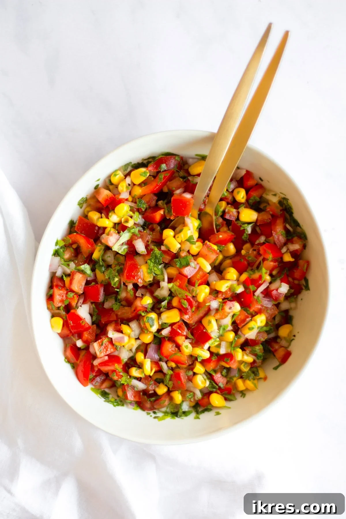 Zesty Sweet Corn Pico de Gallo 6 A beautifully presented bowl of mixed corn salsa, featuring a pair of elegant gold spoons ready for serving.