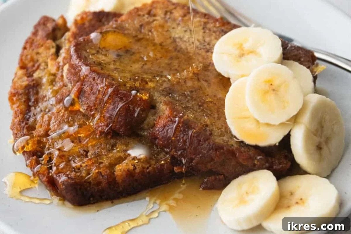 Delicious banana bread French toast topped with fresh banana slices and a drizzle of maple syrup