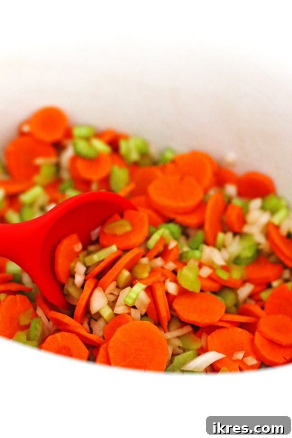 Cozy Slow Cooker Chicken Soup 4 Sliced carrots, celery, and onion being gently mixed with garlic powder inside a crockpot, preparing for slow cooking.