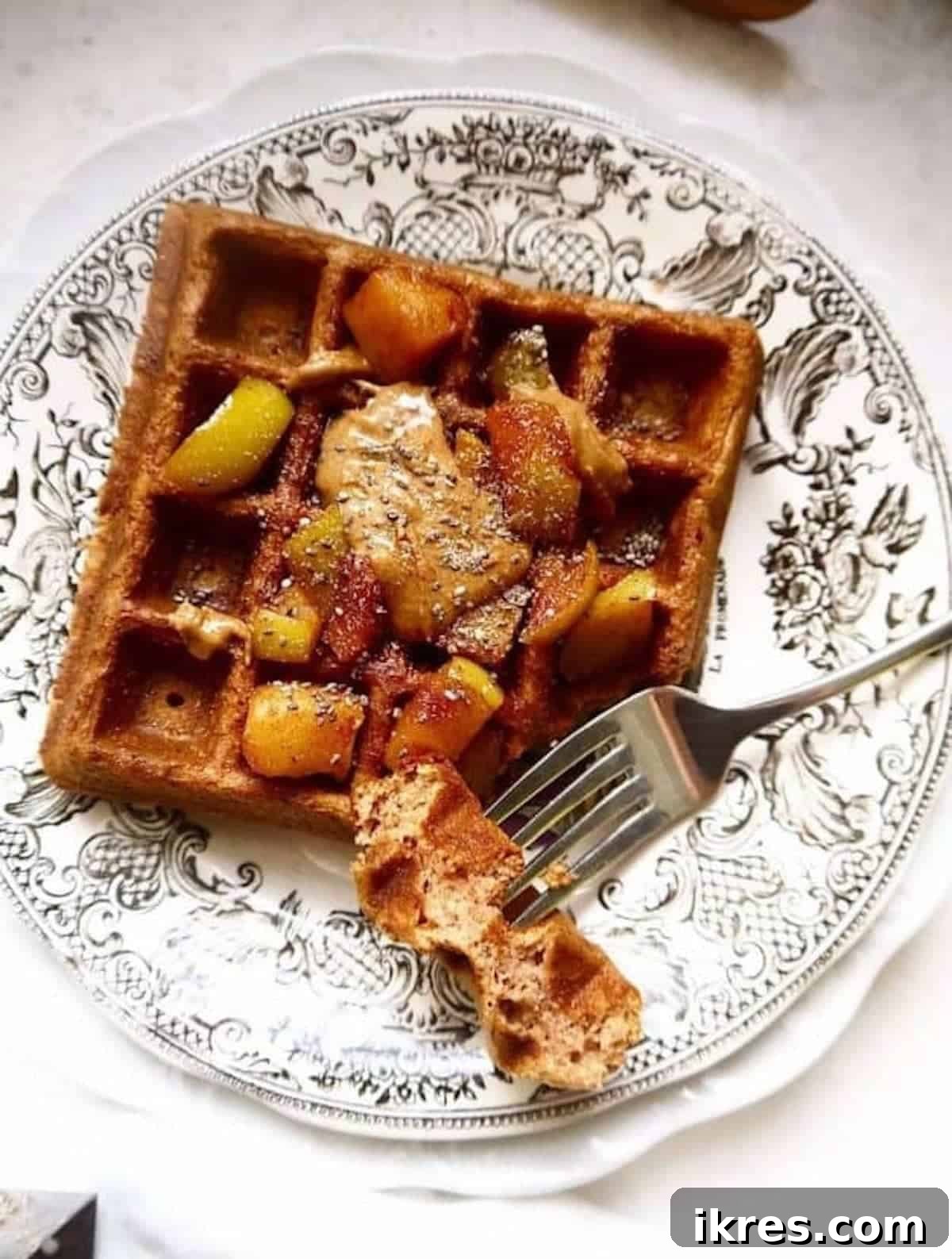 Paleo Gluten-Free Apple Cinnamon Waffles 2 Apple cinnamon waffles on a plate with fresh apple slices and maple compote on top, ready to be enjoyed.