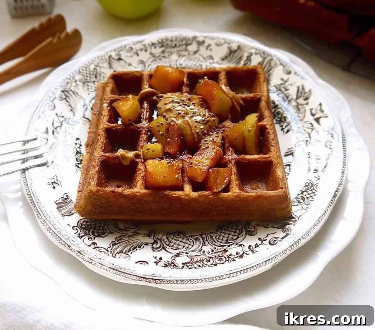 Paleo Gluten-Free Apple Cinnamon Waffles 6 Paleo apple cinnamon waffles served on a plate, topped with more cooked apples, almond butter drizzle, and chia seeds.