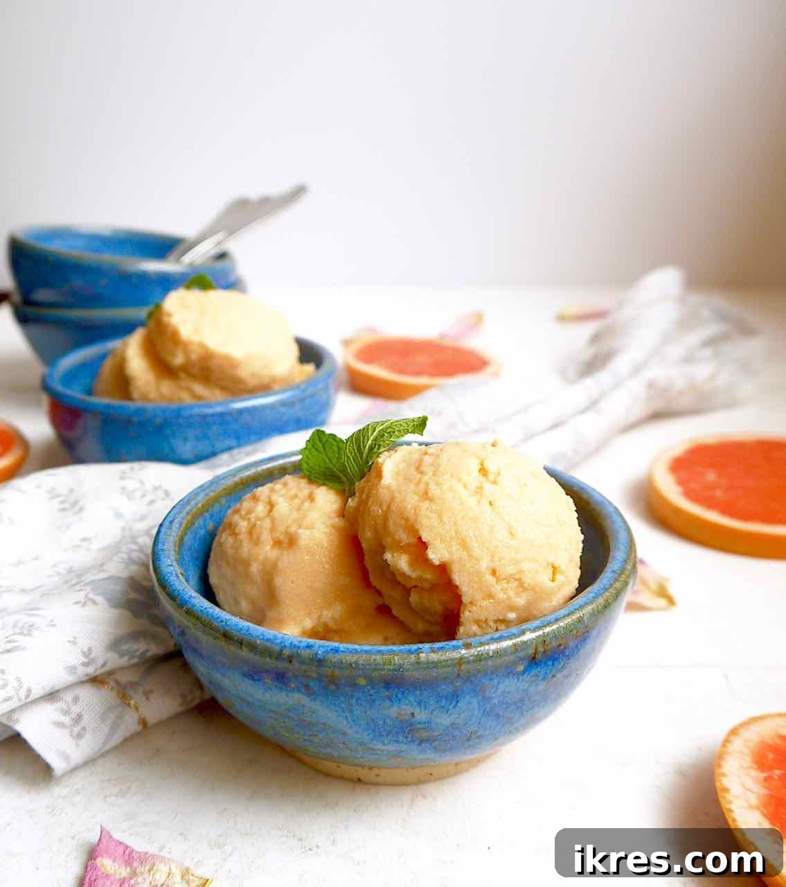 A bowl of vibrant pink grapefruit sorbet with a spoon.