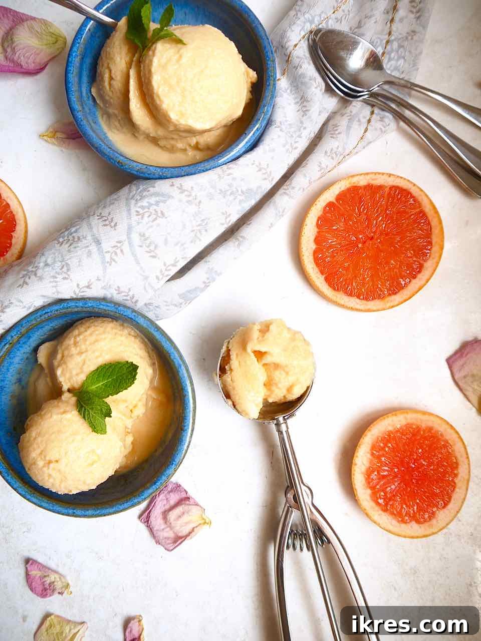 A scoop of creamy grapefruit sorbet in a bowl next to an ice cream scoop.