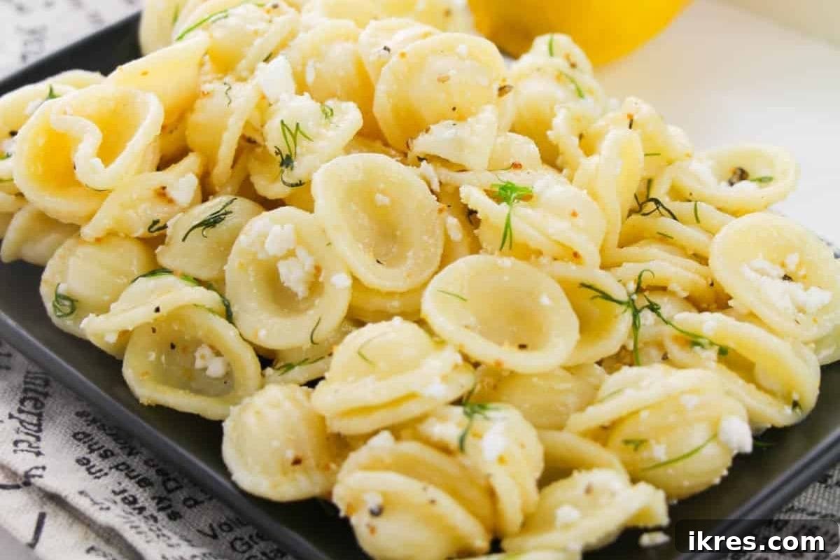 40 Irresistible BBQ Sides 6 A vibrant dill pasta salad with fresh herbs, cheese, and lemon slices, served in a glass bowl.