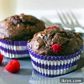 Two dark chocolate raspberry banana muffins on a charming blue plate, ready to be enjoyed.