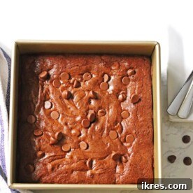 Classic Homemade Brownies neatly arranged in an 8x8 pan, accompanied by plates and spoons.