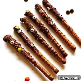 Festive Pretzel Rods dipped in melted chocolate and decorated with crushed candy and whimsical edible eyes.