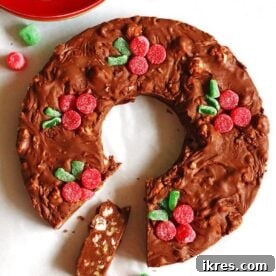 Homemade chocolate fudge artfully shaped as a Christmas wreath, embellished with colorful gumdrops resembling berries.