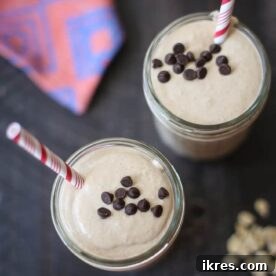 A tall glass of a rich, creamy peanut butter chocolate oat smoothie, garnished with a sprinkle of chocolate chips.