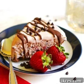 A tempting slice of chocolate ice cream pie on a plate, garnished with a spoon and two fresh strawberries.