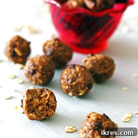 A tempting display of Peanut Butter Energy Balls in front of a red bowl, with one ball showing a delicious bite taken out.