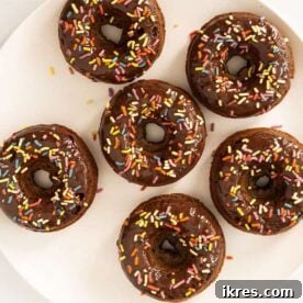 A platter of freshly baked chocolate donuts, lightly glazed, inviting and perfect for a sweet start to the day.
