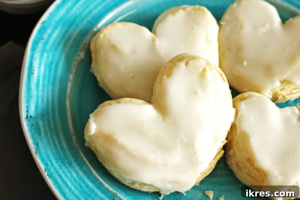 8 Portable Thanksgiving Desserts for Family Fun 2 Golden brown puff pastry hearts drizzled with glaze on a white plate, perfect for dessert