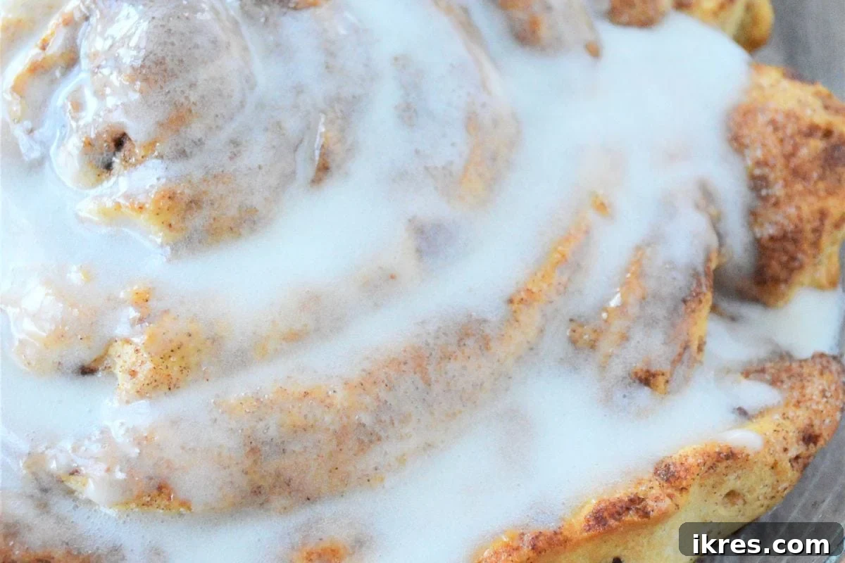 A large, single fluffy cinnamon roll with generous cream cheese frosting, perfect for sharing on Christmas morning.