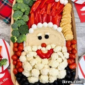 Healthy Santa Snack Board featuring hummus, vegetables, cheese, and crackers arranged festively.