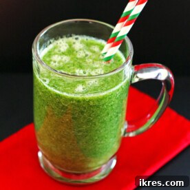 A green Grinchy Green Smoothie made with orange, banana, greens, water, & flaxseed, a healthy holiday drink.