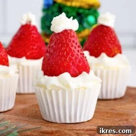 Mini no-bake Santa Hat Cheesecake Bites topped with a strawberry and whipped cream, ideal for festive holiday gatherings.